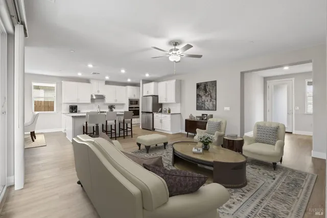 a living room with furniture kitchen view and a chandelier