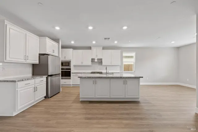 a kitchen with stainless steel appliances granite countertop a stove a sink and a refrigerator