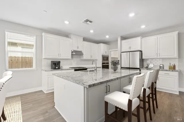 a kitchen with stainless steel appliances granite countertop a table chairs sink refrigerator and microwave