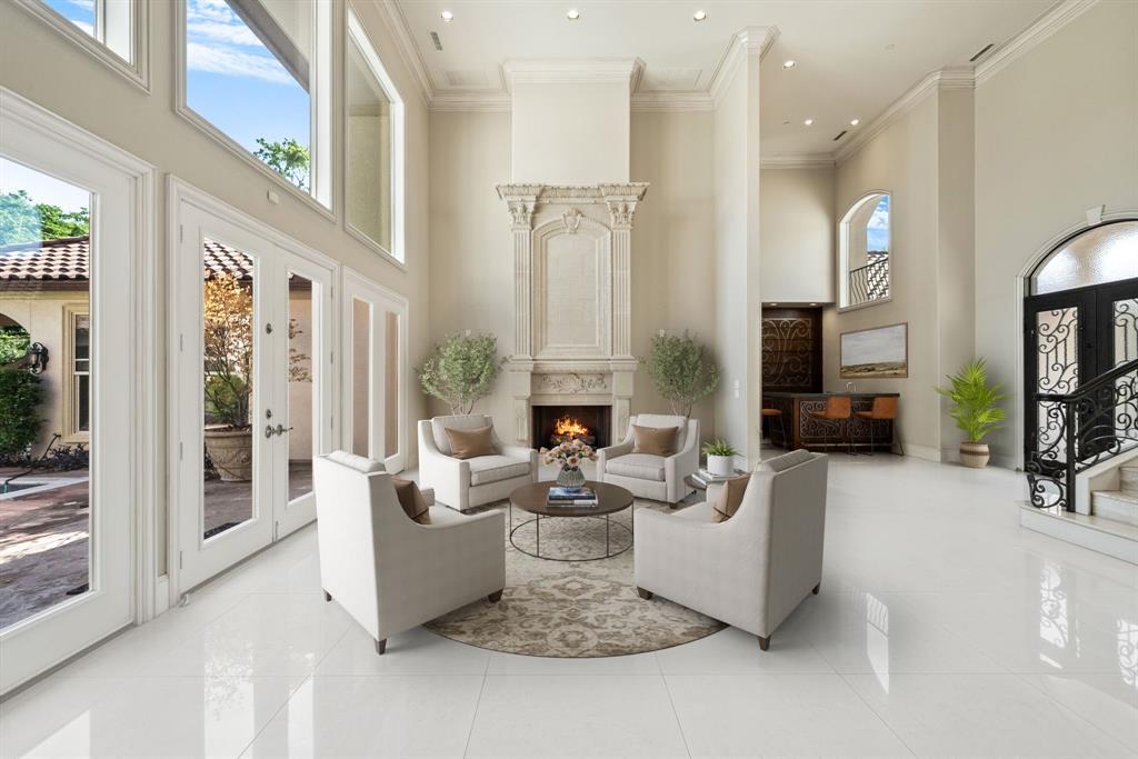 Grand foyer featuring a two-story ceiling, a formal fireplace with an ornate mantel, polished tile flooring, and French doors with transom windows