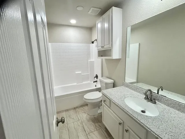 a bathroom with a granite countertop sink toilet and shower
