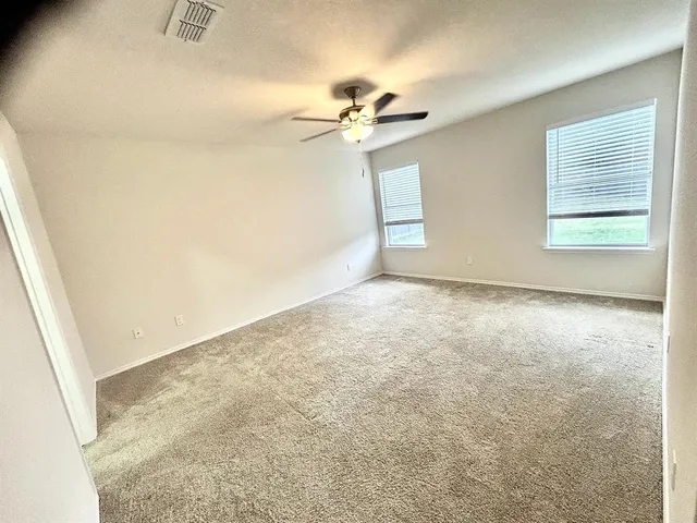 an empty room with windows and fan