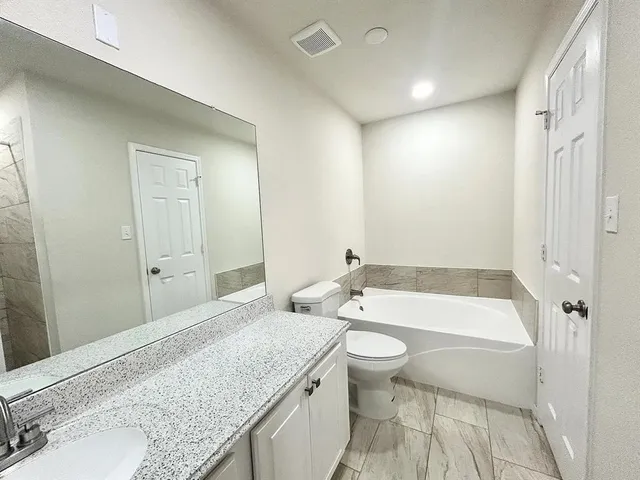 a bathroom with a granite countertop sink a toilet and bathtub