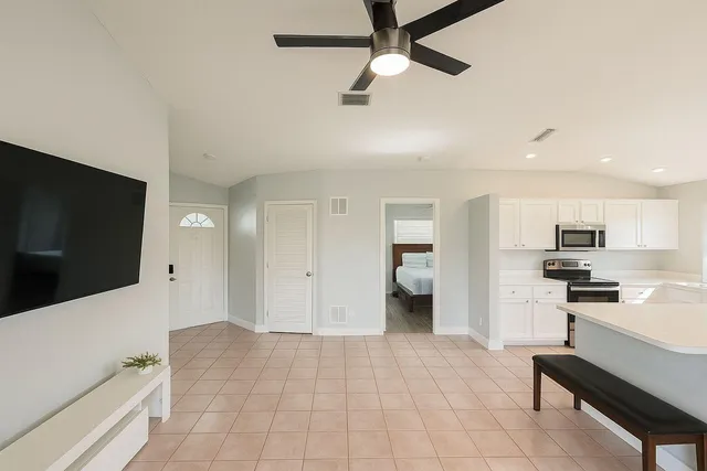 a living room with stainless steel appliances furniture and a flat screen tv