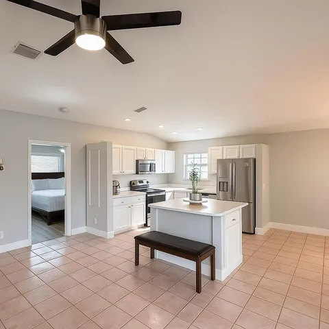 a living room with stainless steel appliances furniture a rug and a kitchen view