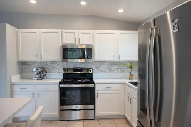 a kitchen with white cabinets and stainless steel appliances
