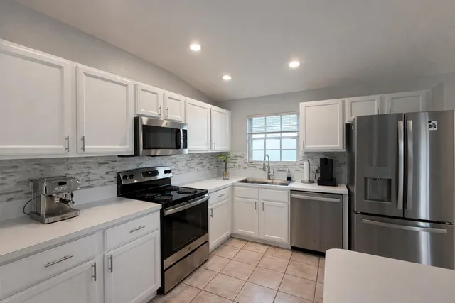 a kitchen with a sink stainless steel appliances and white cabinets