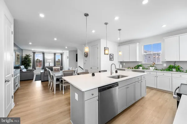 a kitchen with a dining table chairs wooden floor appliances and cabinets