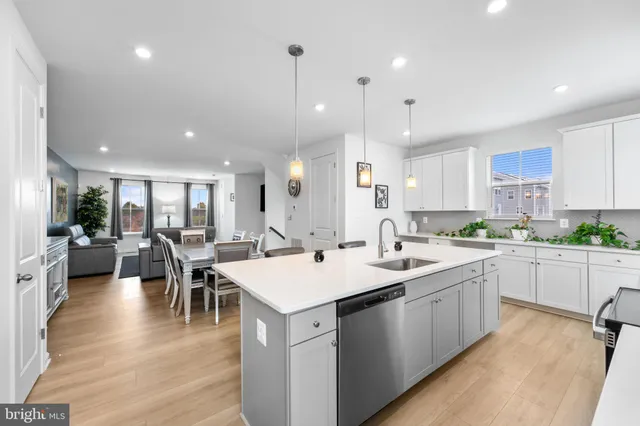 a kitchen with a dining table chairs wooden floor appliances and cabinets