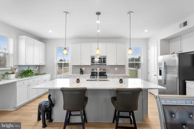 a kitchen with refrigerator a sink and chairs