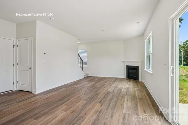 an empty room with wooden floor fireplace and windows