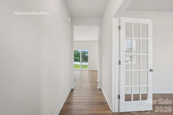 a view of a hallway with wooden floor and a bathroom