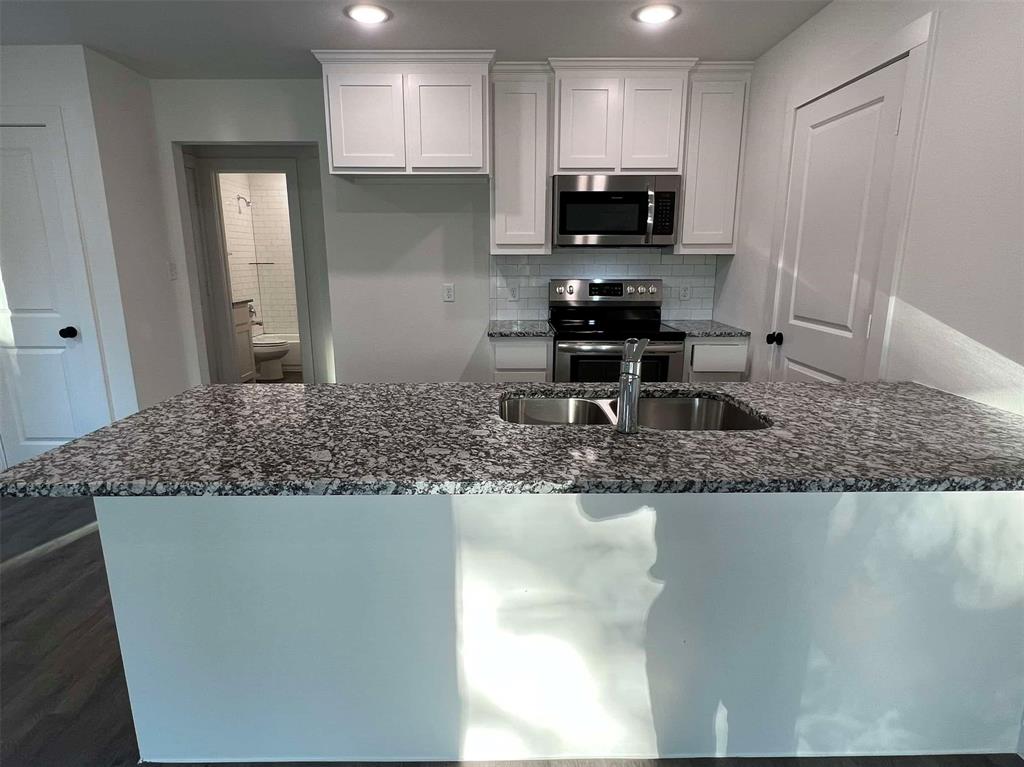 2526 South Fannin Avenue Denison, TX 75020 - Photo 4 of 20 a kitchen with kitchen island granite countertop a sink a stove and refrigerator