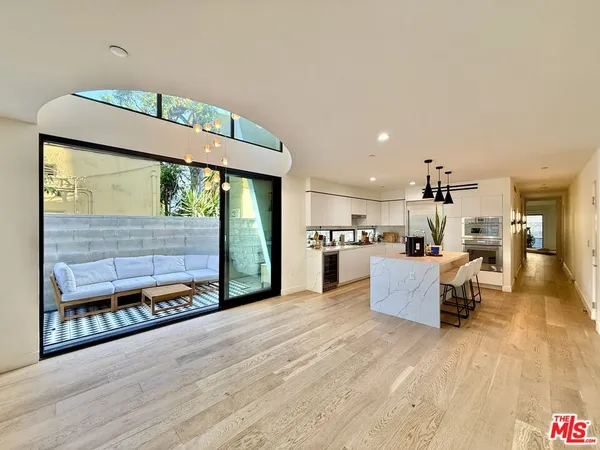a living room with stainless steel appliances kitchen island granite countertop furniture and a large window