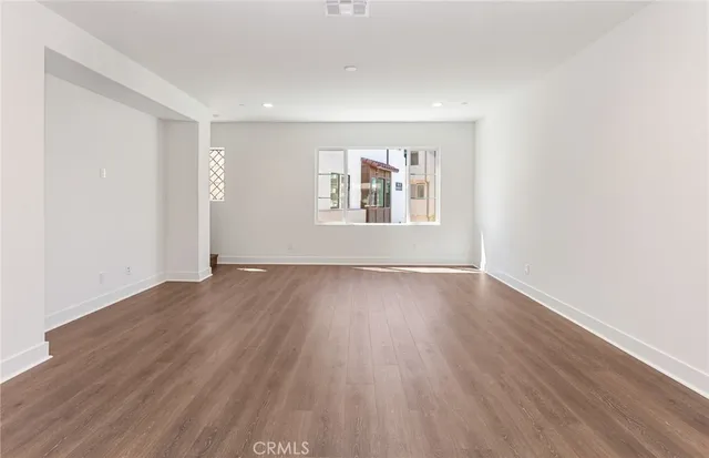 a view of an empty room with wooden floor and windows