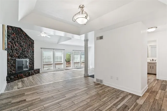 a view of an empty room with wooden floor and a fireplace