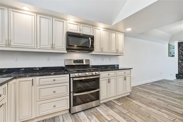 a kitchen with granite countertop white cabinets and stainless steel appliances