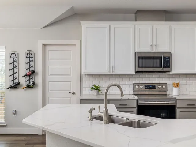 a kitchen with stainless steel appliances a white stove top oven and white cabinets