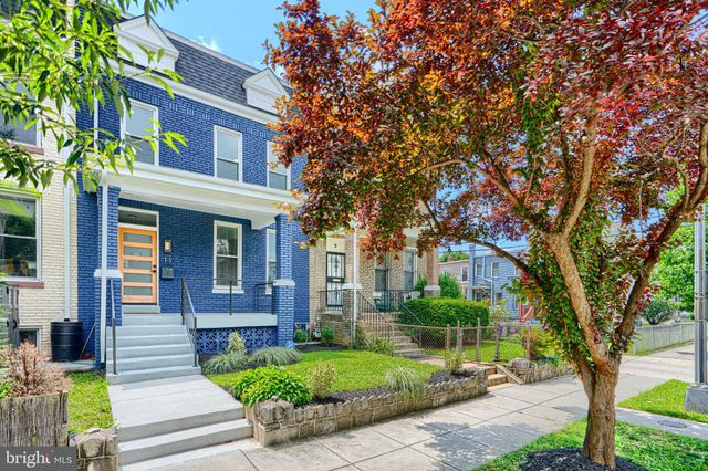 a car parked in front of a brick house with large trees