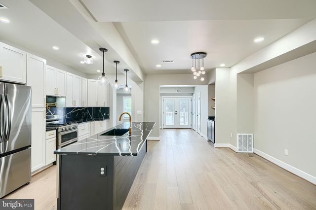 a kitchen that has a sink wooden floor and stainless steel appliances