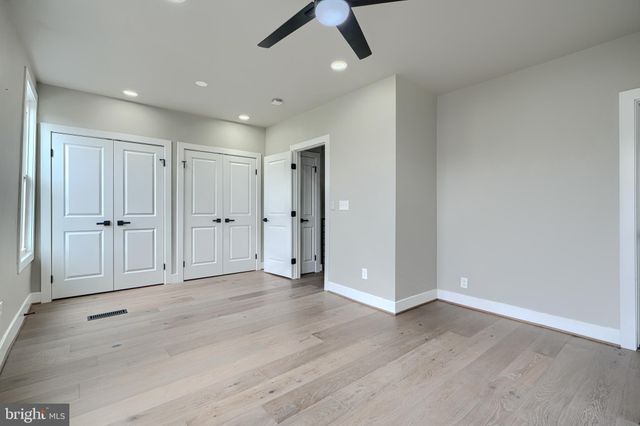 an empty room with wooden floor and a ceiling fan
