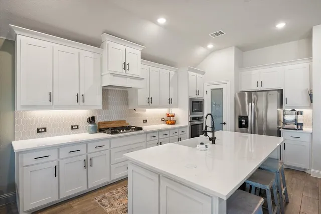 a kitchen with white cabinets and stainless steel appliances