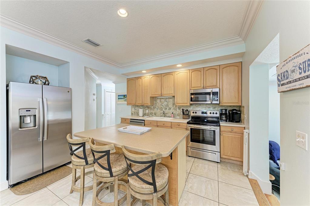 4003 5th Avenue Holmes Beach, FL 34217 - Photo 15 of 56 a kitchen with stainless steel appliances granite countertop a refrigerator a stove top oven a sink dishwasher and white cabinets with wooden floor