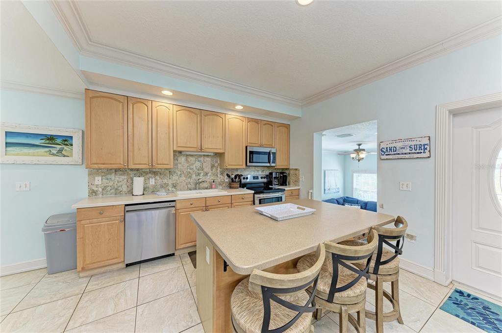 4003 5th Avenue Holmes Beach, FL 34217 - Photo 17 of 56 a kitchen with a dining table chairs and white cabinets