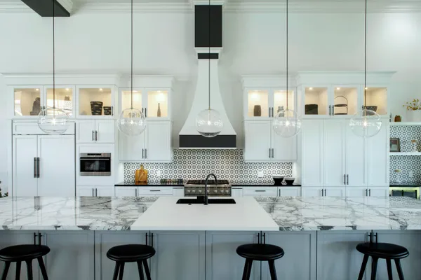 a kitchen with stainless steel appliances kitchen island granite countertop a stove a sink and a white wooden cabinets