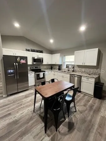 a kitchen with stainless steel appliances kitchen island granite countertop a table chairs and a refrigerator