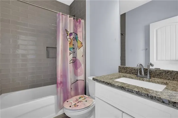 a bathroom with a granite countertop bathtub sink vanity mirror and toilet