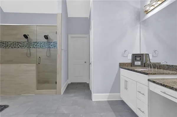 a bathroom with a granite countertop sink a mirror and shower