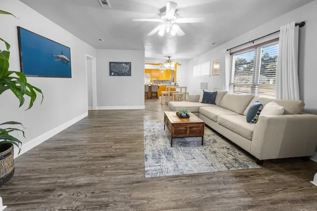 an empty room with wooden floor fan and window