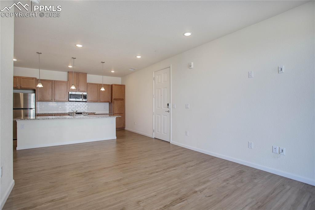 3865 Presidio Point, Unit 101 Colorado Springs, CO 80920 - Photo 2 of 20 a large kitchen with white cabinets and wooden floor