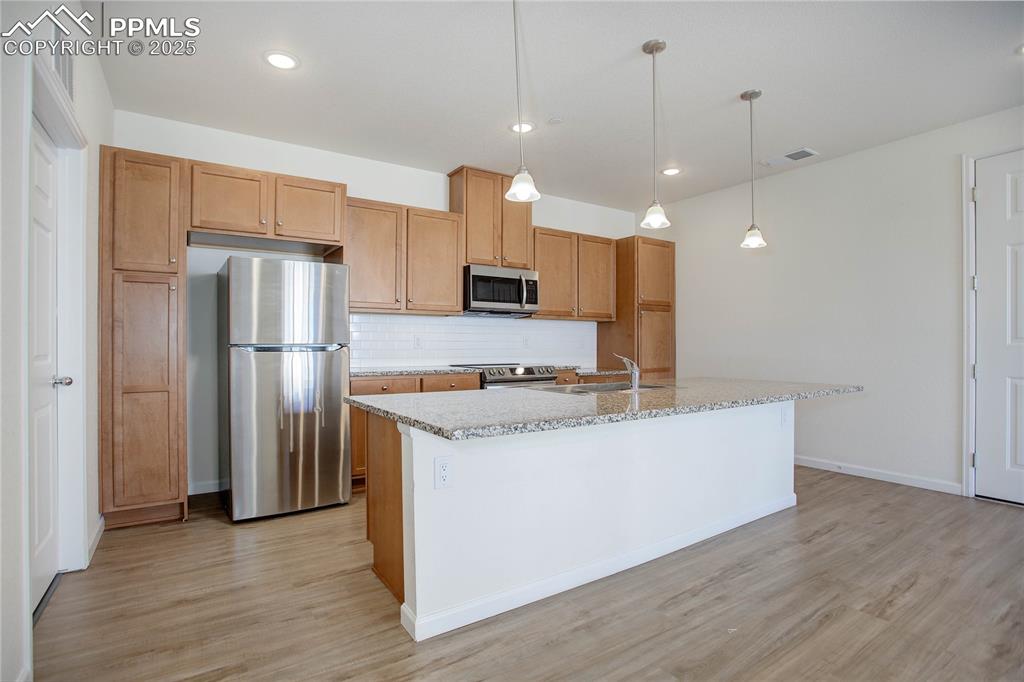 3865 Presidio Point, Unit 101 Colorado Springs, CO 80920 - Photo 3 of 20 a kitchen with stainless steel appliances granite countertop a refrigerator a sink and a stove