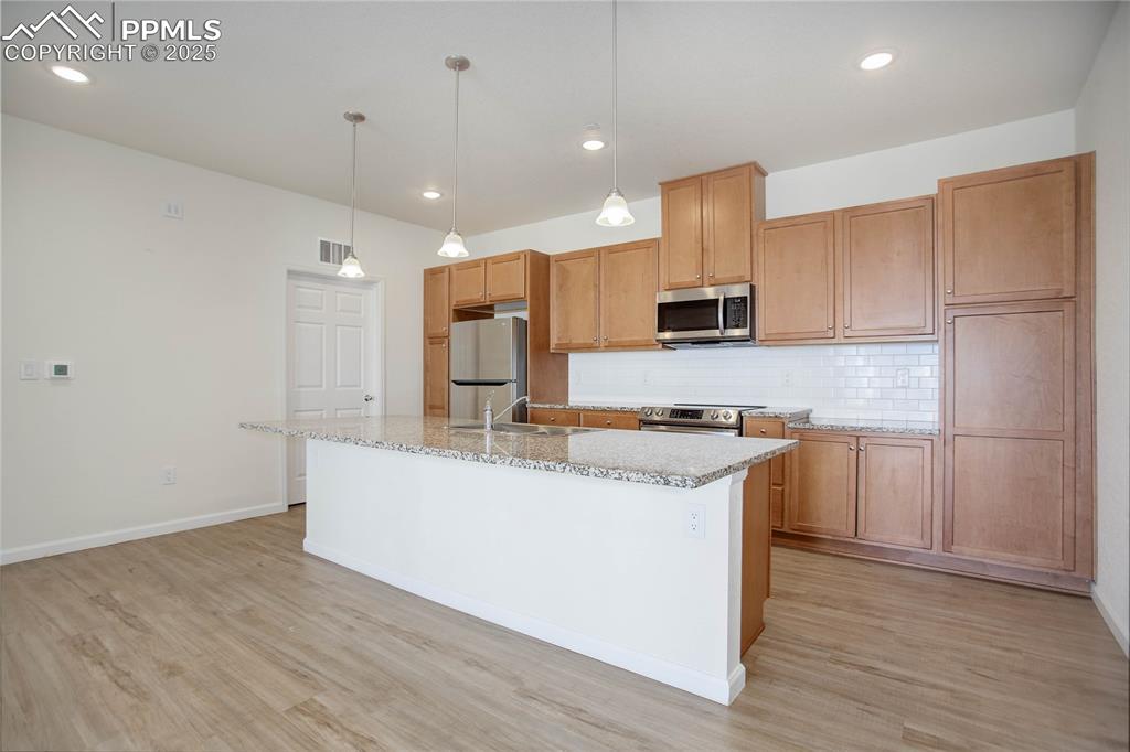 3865 Presidio Point, Unit 101 Colorado Springs, CO 80920 - Photo 4 of 20 a large kitchen with stainless steel appliances granite countertop a sink a stove and a refrigerator
