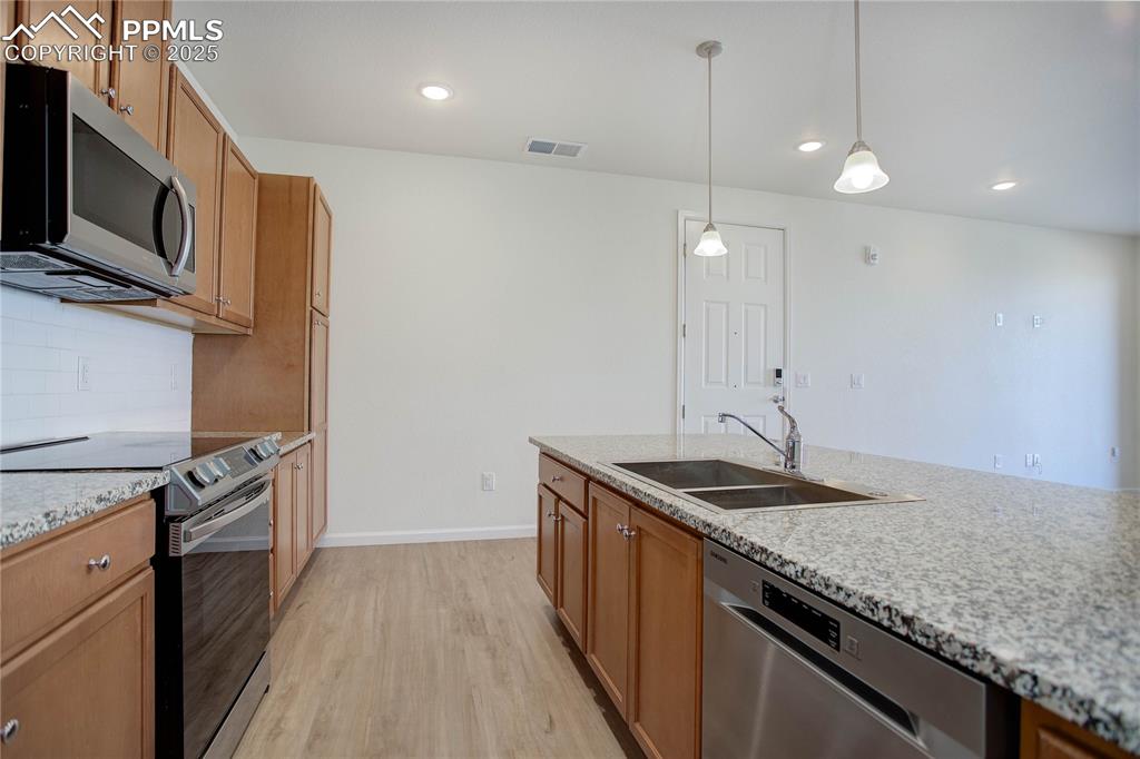 3865 Presidio Point, Unit 101 Colorado Springs, CO 80920 - Photo 5 of 20 a kitchen with stainless steel appliances granite countertop a sink a stove and a wooden floor