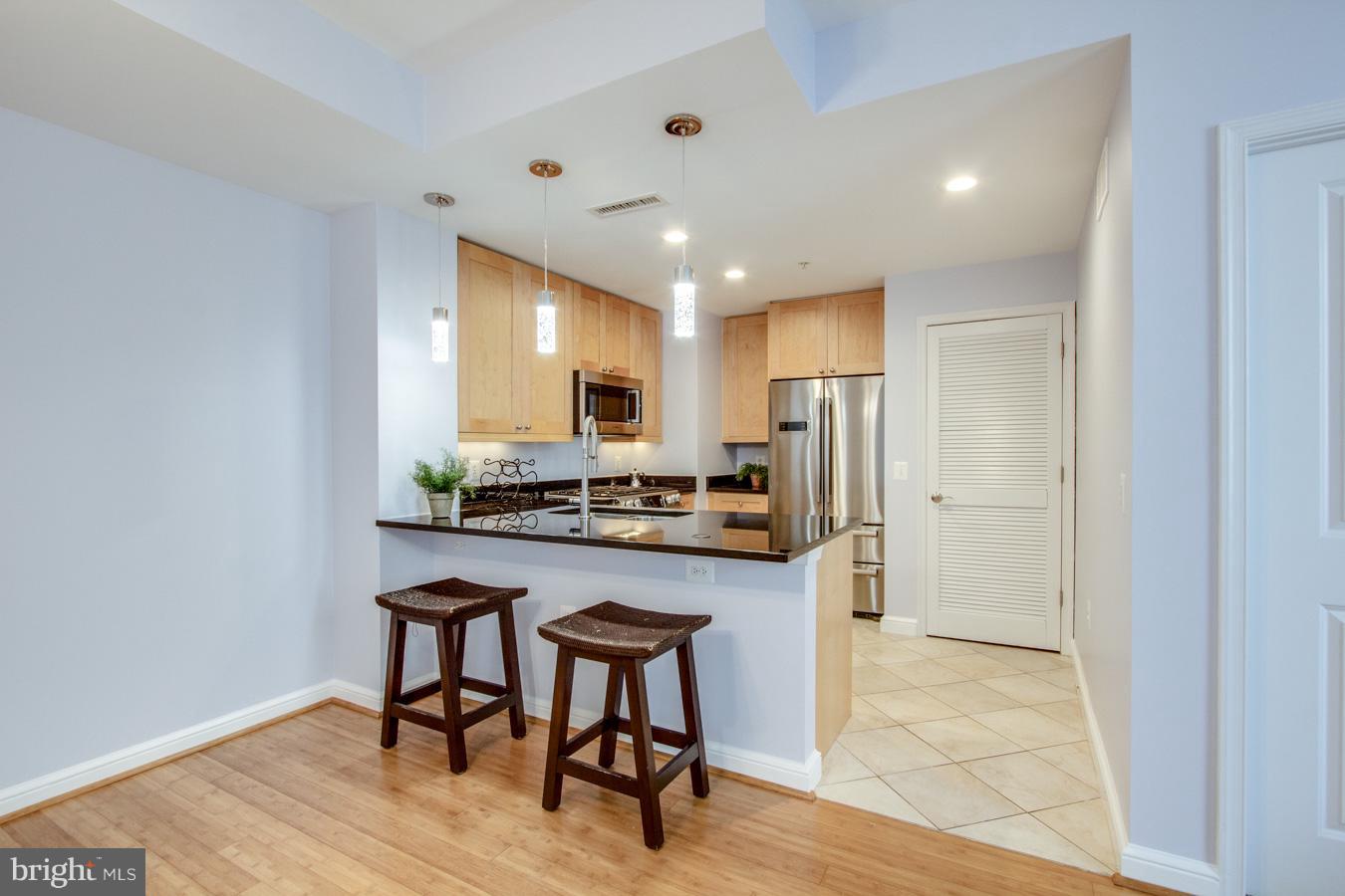 11990 Market Street, Unit 1308 Reston, VA 20190 - Photo 8 of 30 a kitchen with stainless steel appliances kitchen island granite countertop a refrigerator and a stove top oven