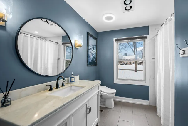 a bathroom with a granite countertop toilet a sink and a mirror