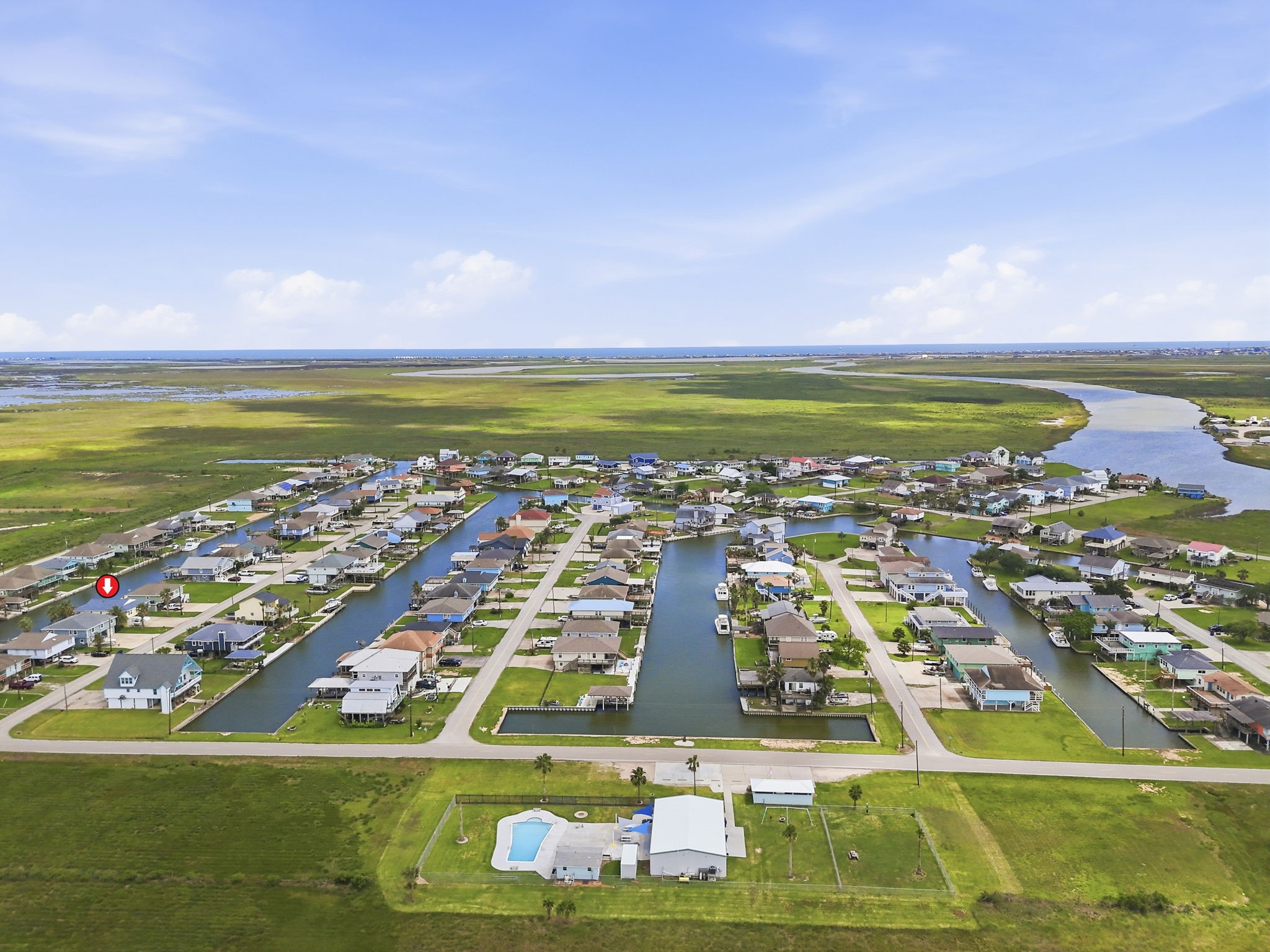 119 Sand Shoals Road Freeport, TX 77541 - Photo 26 of 34 Subdivision aerial with subject pinned — Hide-A-Way on the Gulf canal layout, community pool and clubhouse visible foreground, marsh and Gulf horizon to the south.