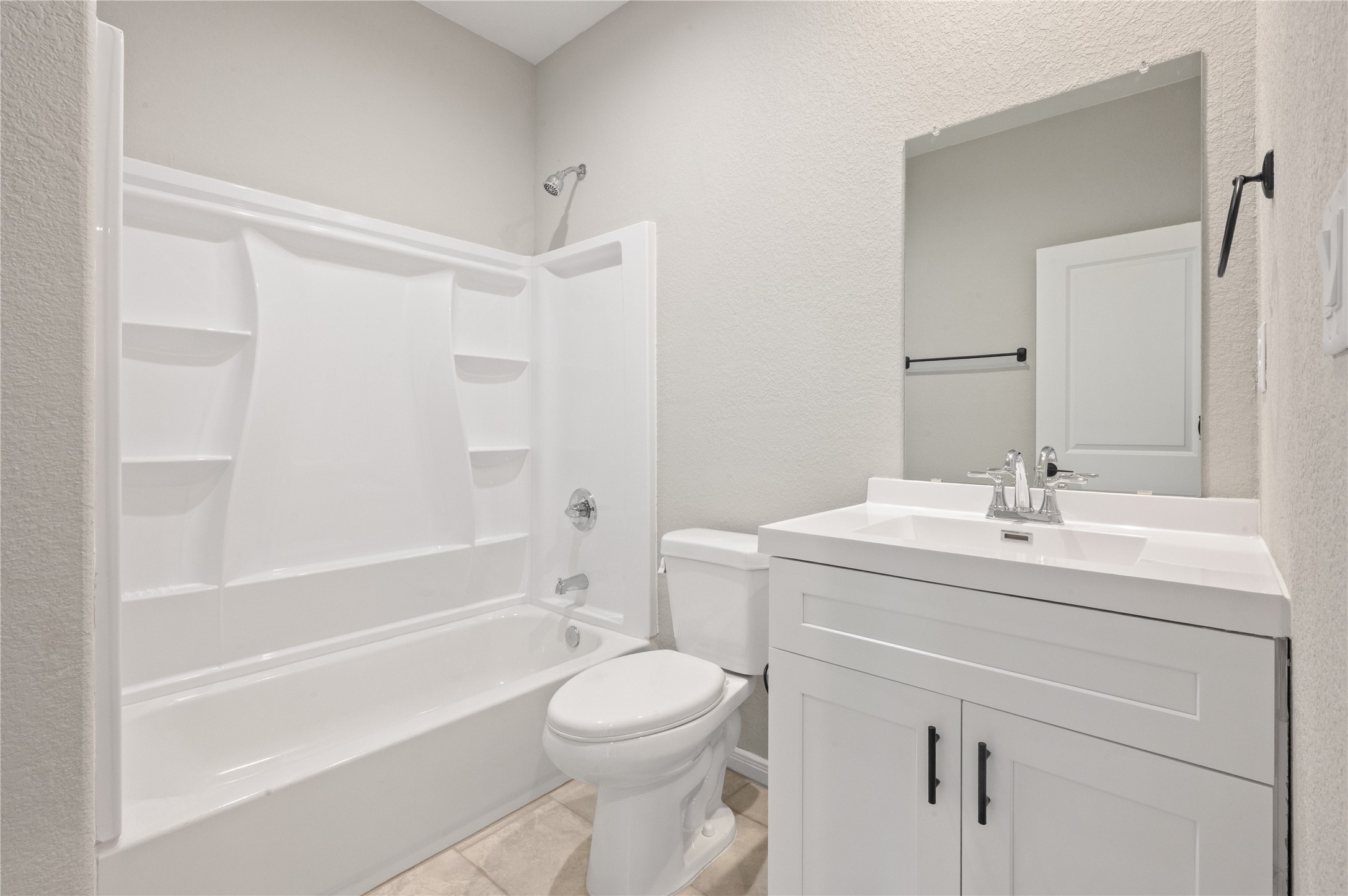 14010 Longstreet Road, Unit 2 Willis, TX 77318 - Photo 11 of 29 This bathroom features a clean, modern design with a white bathtub and shower combo, a sleek white vanity with a large mirror, and neutral-colored walls and flooring.