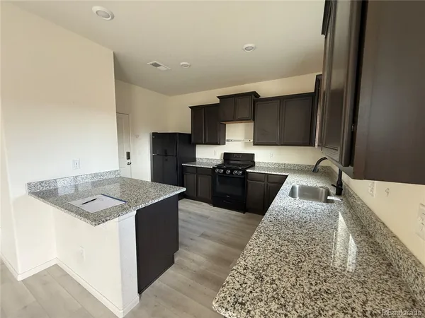 a kitchen with granite countertop a sink and a stove top oven with wooden floor