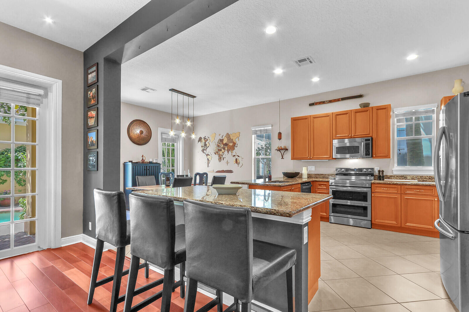 122 Inkberry Drive Jupiter, FL 33458 - Photo 10 of 56 a kitchen with stainless steel appliances granite countertop a stove top oven a sink dishwasher a dining table and chairs with wooden floor