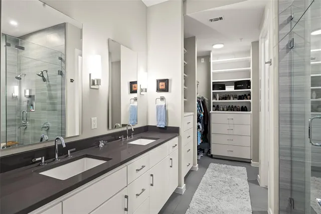 a bathroom with a granite countertop sink two mirror and shower