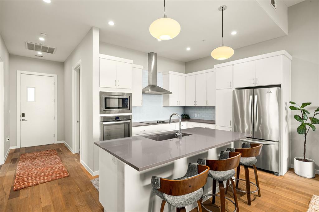 5921 Hiline Road, Unit 2404 Austin, TX 78734 - Photo 6 of 36 a kitchen with granite countertop a table chairs stainless steel appliances and wooden floor
