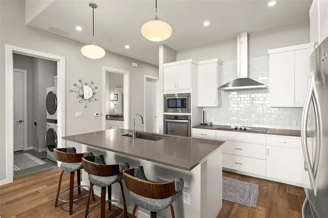 a kitchen with stainless steel appliances granite countertop a dining table chairs refrigerator and sink