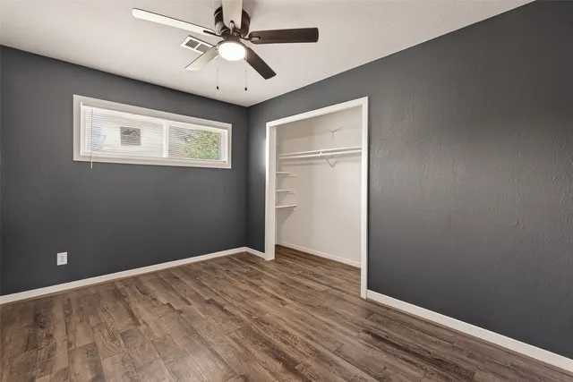 wooden floor in an empty room with a chandelier fan