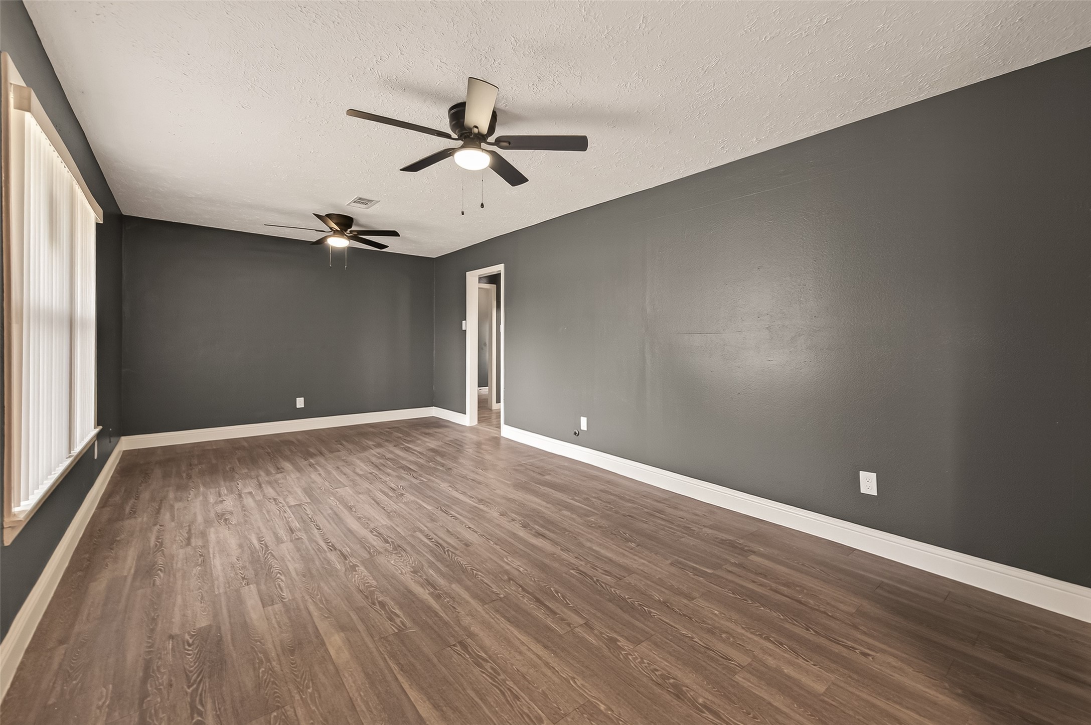2619 Sinclair Street Pasadena, TX 77503 - Photo 4 of 29 an empty room with wooden floor fan and windows