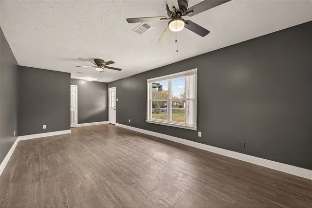 a view of a big room with wooden floor and windows