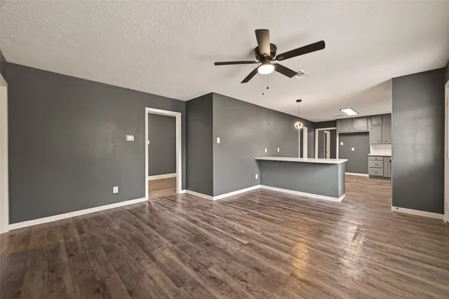a view of an empty room with window and wooden floor
